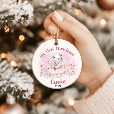 Personalized Bunny Baby First Christmas Ornament featuring a cute bunny in a pink dress with flowers, custom name Cadie 2025, that perfect keepsake decoration for a baby girl’s first Xmas.