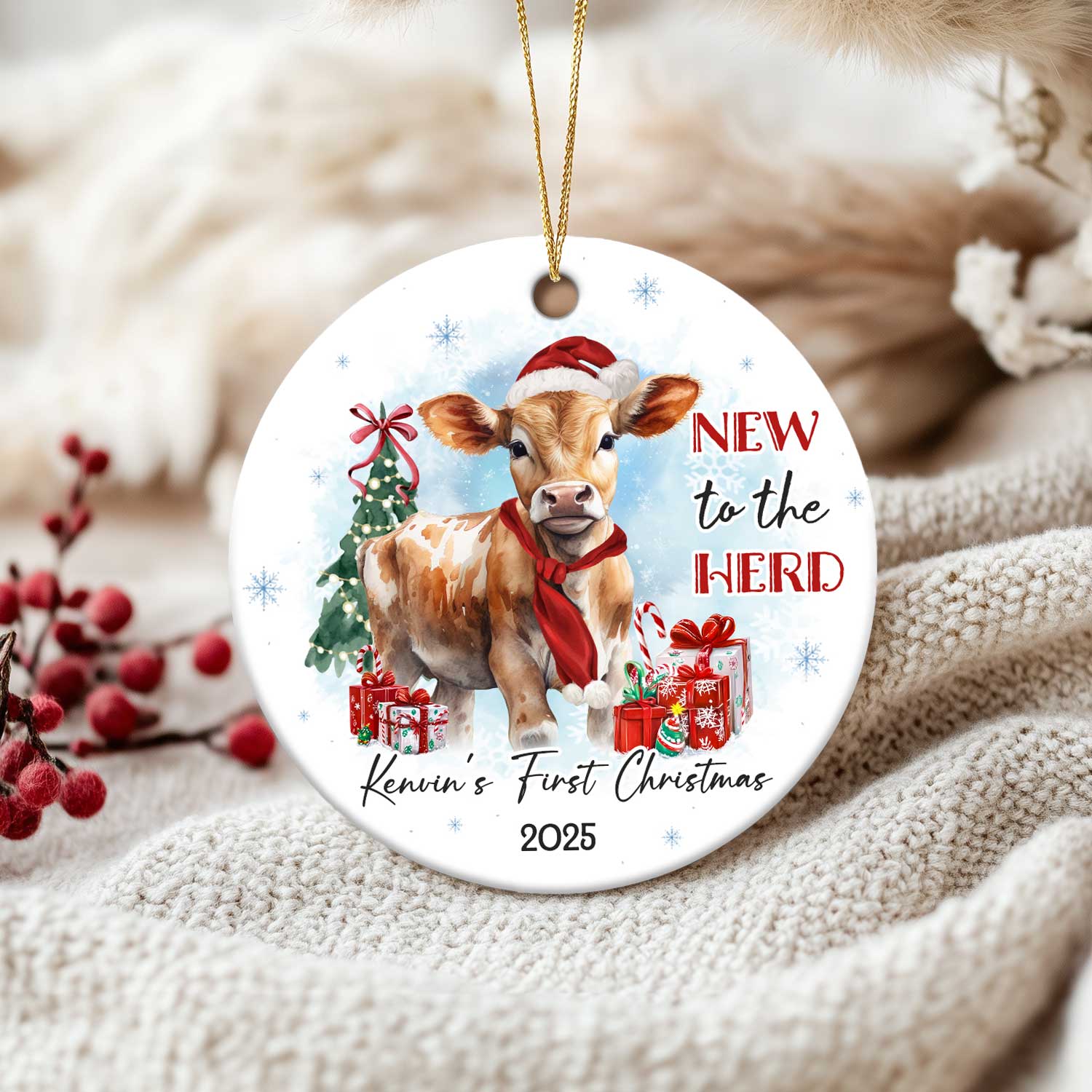 Cow Baby First Christmas Ornament featuring a cute calf in a Santa hat and red scarf, surrounded by gifts and a Christmas tree, with the text New to the Herd and customized with baby’s name and year
