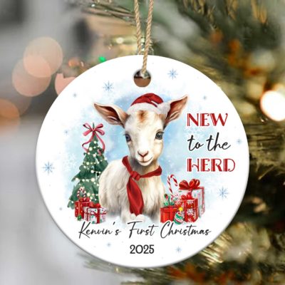 Personalized Baby's First Christmas Ornament featuring a cute baby goat wearing a Santa hat and red scarf, with Christmas tree, presents, and text New to the Herd, customized with baby’s name and year.