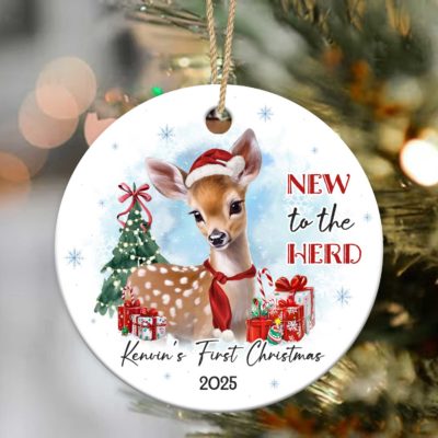 Baby's First Christmas Ornament featuring a cute baby deer wearing a Santa hat and red scarf, with Christmas tree, presents, and the text New to the Herd, customized with baby’s name and year.