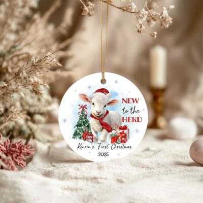 Baby Lamb Ornament featuring a cute lamb in a Santa hat and red scarf, with Christmas tree, gifts, and text New to the Herd, customized with baby’s name and year.