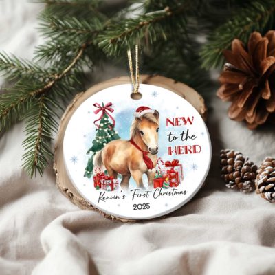 Personalized Horse Ornament For Kids featuring a cute pony wearing a Santa hat and red scarf, with Christmas tree, gifts, and text New to the Herd, customized with baby’s name and year.